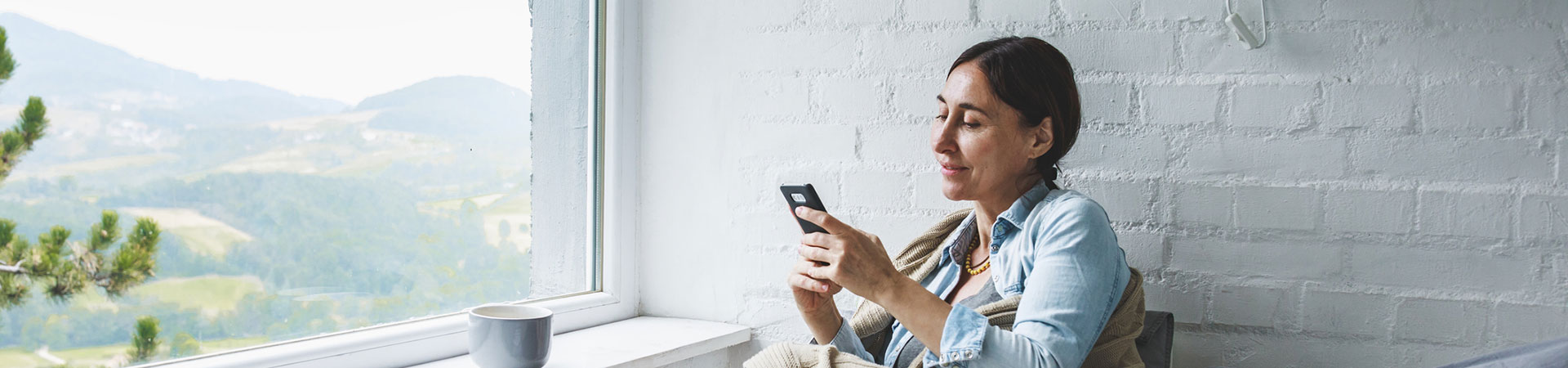 Lady using her smartphone while relaxing in her home